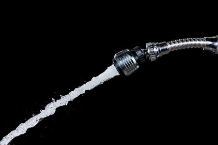 Water with bubbles flows down from the water tap against a black backgroundの写真素材