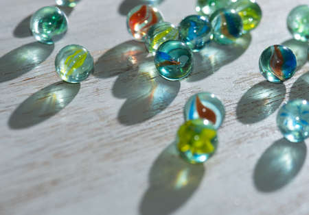 Colorful glass marbles with sun reflection, light and shadow on wooden backgroundの写真素材