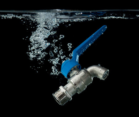 Steel water tap or faucet with water splash on a black background.の写真素材