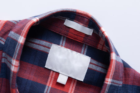 White blank clothing tag label on new shirt fabric texture background