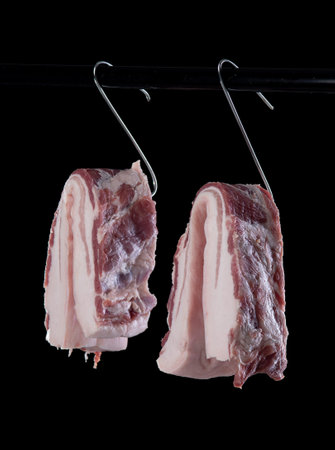 Belly pork meat hanging from the hook, isolated on white background.の写真素材