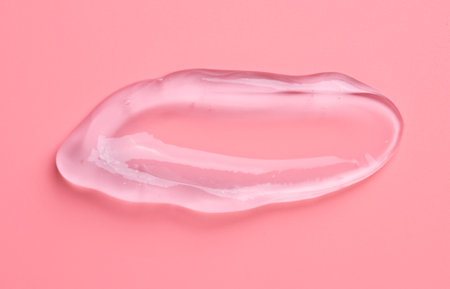 Transparent gel drop on pink background. Liquid gel cosmetic stain texture. Beauty serum drop
