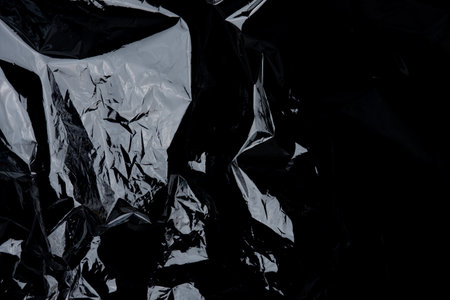 Transparent plastic wrap on the black background. Plastic bag texture