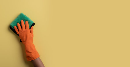 Closeup of a hand in a orange latex glove using a green towel to cleanの写真素材
