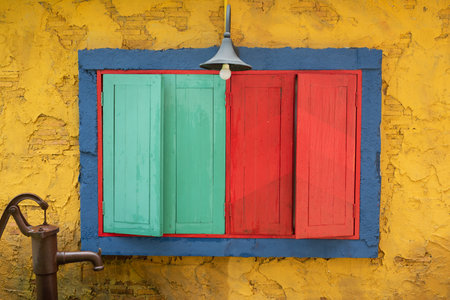 old wooden windows with green and red colored window sits in the middle of an architectural built structureの写真素材