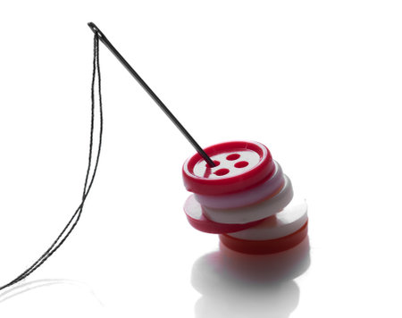 Sewing needle and button isolated on white backgroundの写真素材