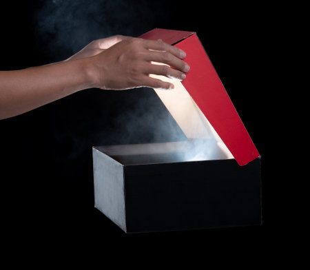 hand hold and open a mysterious box, smoke float up from box over dark backgroundの写真素材