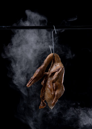 Spiced duck or Pot-stewed duck are hung by the stainless hooks with smokeの写真素材