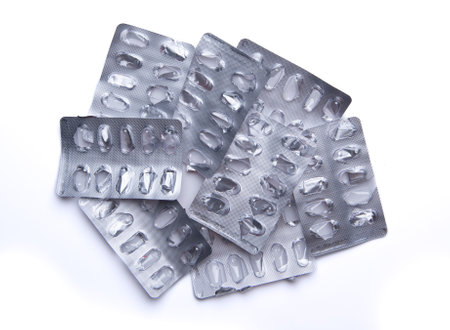 Used empty pill blister pack, discarded silver medicine packs, isolated on white background
