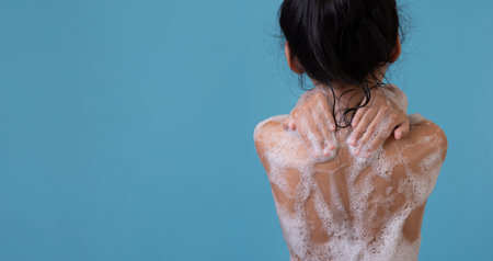 Girl in the bath with bubbles. Happy child enjoying bath time,Back view.