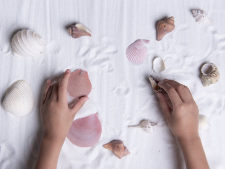 little girl holding sea shells on white sand. Sea summer vacation background . Top viewの写真素材