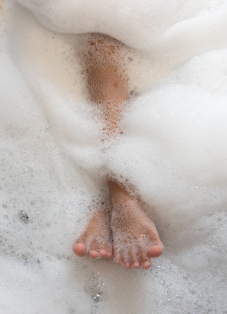 Woman legs in bath foam. Top view. Enjoying and relaxationの写真素材