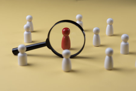 A magnifying glass and a red wooden figures with blur business man who search for someone who âs special person. Concept of Human resources management and recruitment.の写真素材