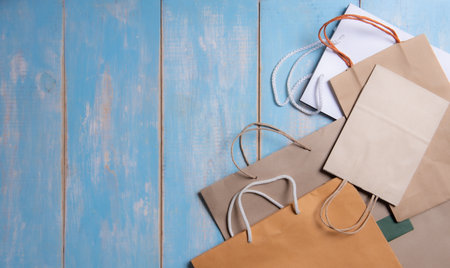 Kraft paper eco bag, top view and flat lay. Brown and white Kraft package on blue wood backgroundの写真素材