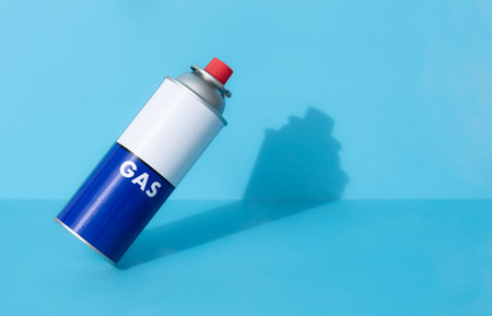 Portable gas cylinder for portable gas appliances with closed red cap on blue backgroundの写真素材