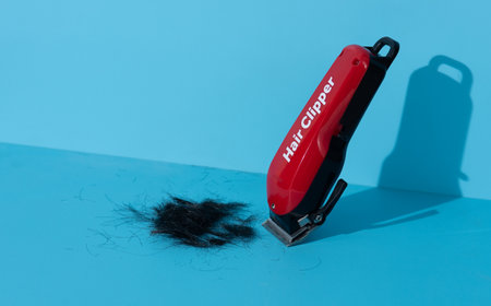 Black and red battery operated hair clippers on blue backgroundの写真素材