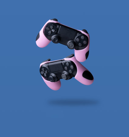 Flying air gamepads from a game console on a blue background. The concept of gamesの写真素材