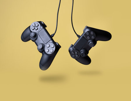 Flying air gamepads from a game console on a yellow background. The concept of gamesの写真素材