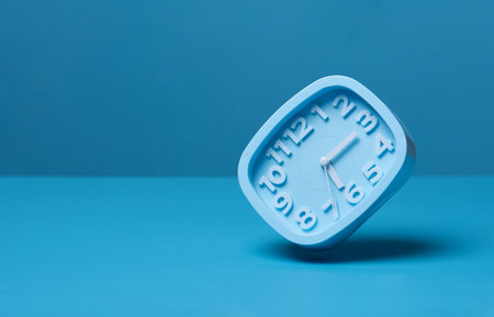 Modern alarm clock on pastel blue background. Minimal concept.の写真素材