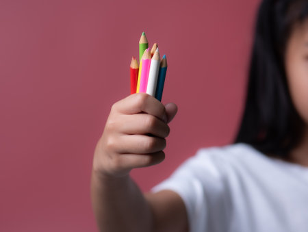 Children's hand holding colored pencilsの写真素材