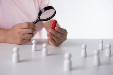 Hand using magnifier to find red wooden figure. leaders for business success, Leadershipの写真素材