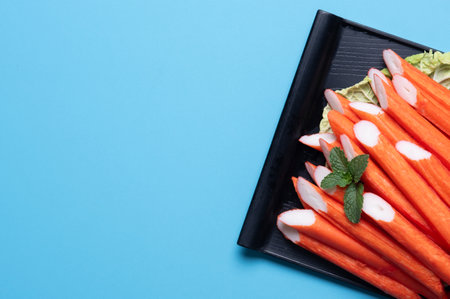 Crab sticks on a black plate ,blue background.top viewの写真素材