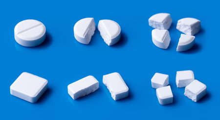 White broken pills lie on a blue background.Pharmacy medicament concept.の写真素材