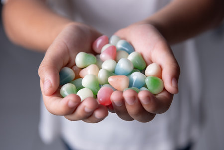 Multicolored candies in the hands of a childの写真素材