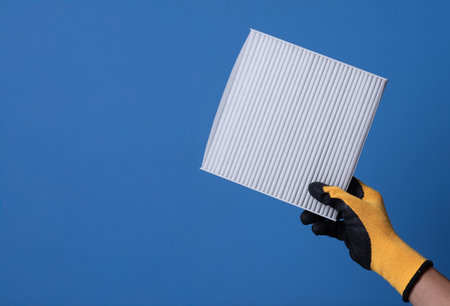 Hand holding cabin air filter auto on blue backgroundの写真素材