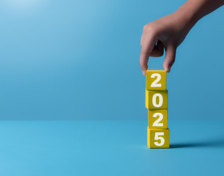 New project growth concept in 2025, Preparation for happy new year , Hand of man flip wooden cube from 2024 to 2025 on blue background, minimal style.の写真素材