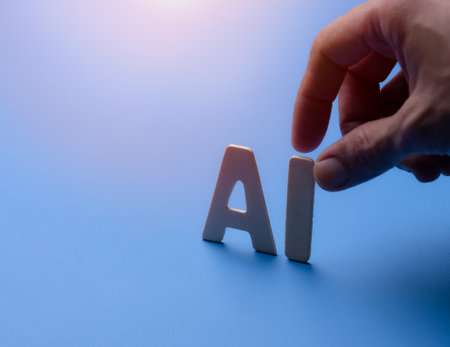 Hand pick the wooden AI letters on blue background.の写真素材