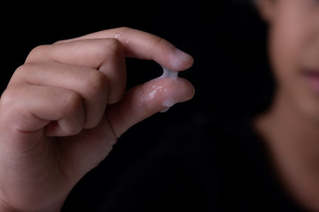 Sticky cosmetic lotion on the finger on black backgroundの写真素材