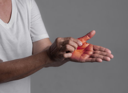 Woman in her 70s suffering from pain in hands and fingers, arthritis inflammation. Red highlightの写真素材