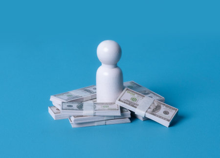 Red wooden figures on stacks of banknote on blue background. Business concept.の写真素材