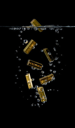 Many gold bars falling into water on black background,Fall in gold prices.の写真素材