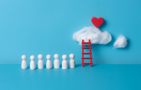 Wooden people figures with serene wooden ladder and a red heart-shaped cloud floating on a blue backgroundの写真素材