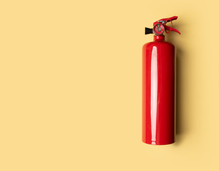 Red fire extinguisher on yellow background for safety and protection against fireの写真素材