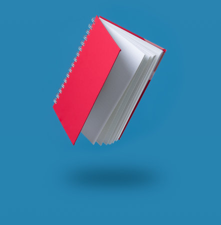 Floating Book,Book is opened and flying through the air isolated on blueの写真素材
