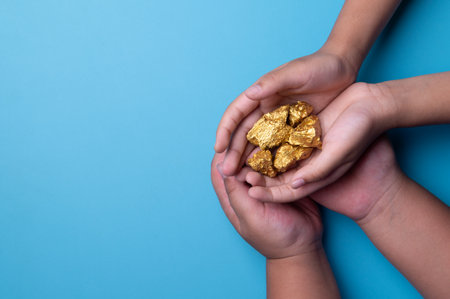 Hands holding gold nuggets on blue backgroundの写真素材