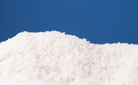 Pile of white rice grains arranged against a blue backgroundの写真素材