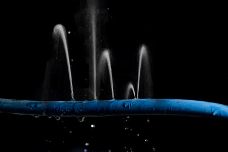 Water leaking on rubber water hose on dark background