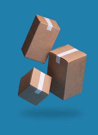 Closed and taped cardboard parcel boxes falling on blue background, Ideal for Shipping, Deliveryの写真素材