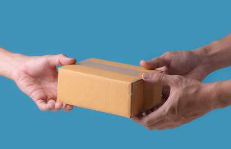 Cardboard boxes in hands. Blank brown parcel boxes on light blue background. Mock up. Packaging, shopping, free shipping, delivery conceptの写真素材