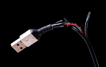 Broken black usb cable on dark background. old wire with dust.
