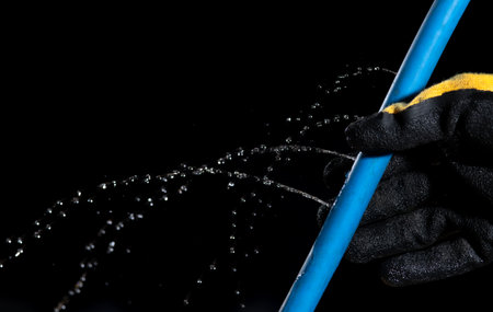 Water leaking on rubber water hose on dark backgroundの写真素材