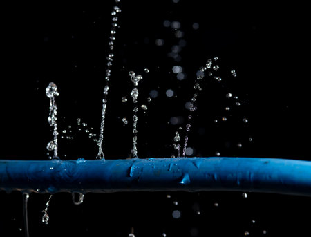 Water leaking on rubber water hose on dark backgroundの写真素材