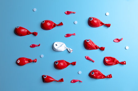 A group of red fish balloons surrounded one white fish. Top view