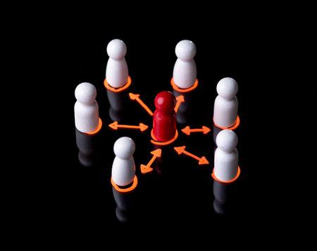 Red wooden figure at center of a network of white wooden figuresの写真素材