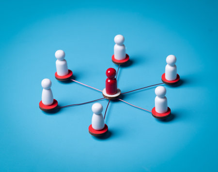 Red wooden figure at center of a network of white wooden figuresの写真素材