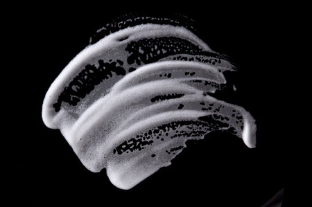 White soapy foam texture. Shampoo foam with bubbles.White facial foam creamy bubble soap sponge isolated on black background.の写真素材